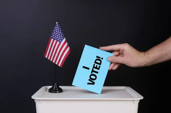 Voter holds blue envelope with I Voted! text