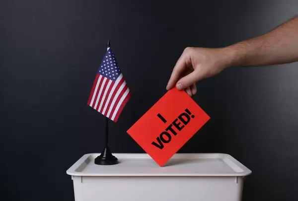 Voter holds red envelope with I Voted! text