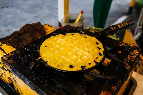 Waffelzubereitung im Eisen auf historischem Ofen