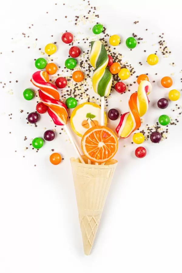 Waffle cone with colorful bright candy on white background, top view