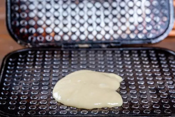 Waffle iron with dough on it in the kitchen