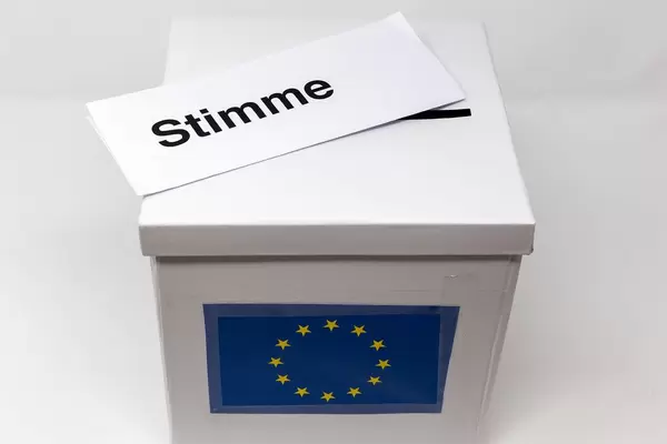 Wahlschein mit dem Aufdruck "Stimme" liegt auf einer EU-Wahlurne, um an der Europawahl teilzunehmen