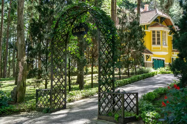 Walkway through a Wooden Arch with Plants leading to Le Roi Villa in the Park of Bao Dai King Palace 1 in Da Lat, Vietnam