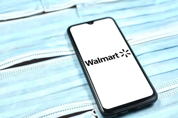 Walmart logo on smartphone screen over the face masks. Global company during coronavirus crisis