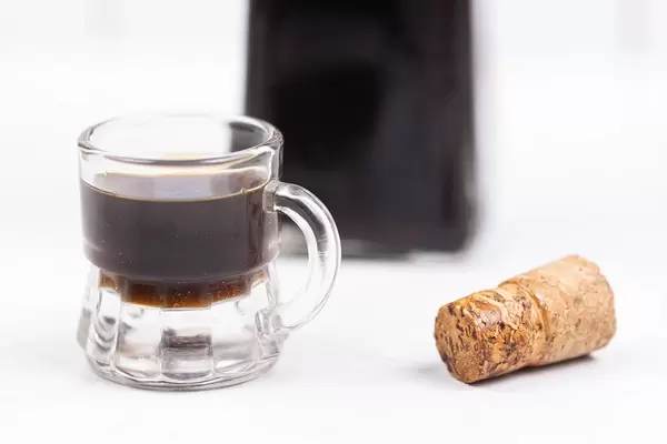 Walnut Liqueur in the glass with the bottle in the background