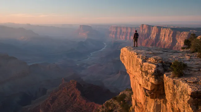 Wanderer auf Felsvorsprung im Grand Canyon bei Sonnenaufgang