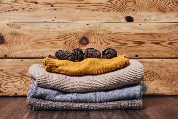 Warm sweaters and pine cones on wood