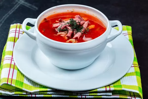 Warme Soljanka Suppe in einer Terrine, auf einem grünen Küchentuch