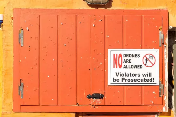 Warning sign "No drones are allowed - violators will be prosecuted" at touristic spot in Santorini