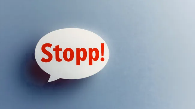 Warnschild 'Stopp' in Sprechblase auf blauem Hintergrund