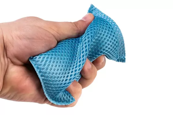 Waschender Schwamm des blauen Tellers in der Hand