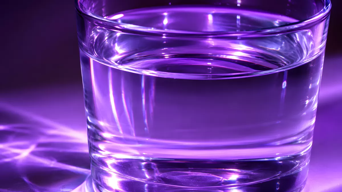 Wasserglas mit violettem Lichtreflex in Nahaufnahme