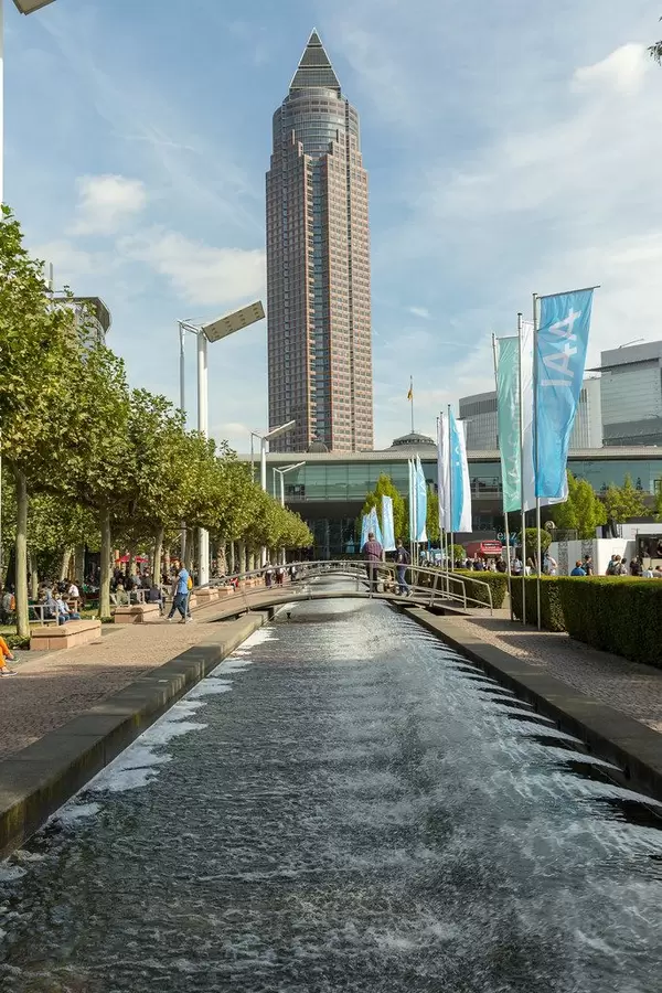 Wasserlauf mit kleinen Brücken und IAA-Fahnen am Messegelände, mit Blick auf den MesseTurm in Frankfurt am Main