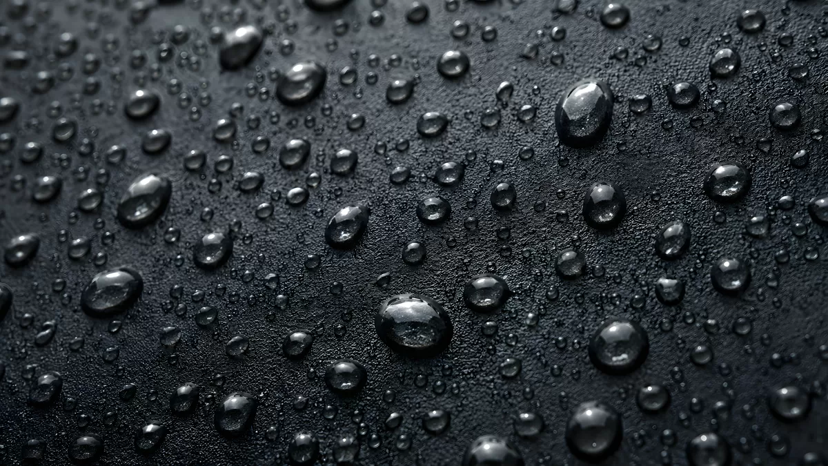 Wassertropfen auf schwarzer Oberfläche in Nahaufnahme