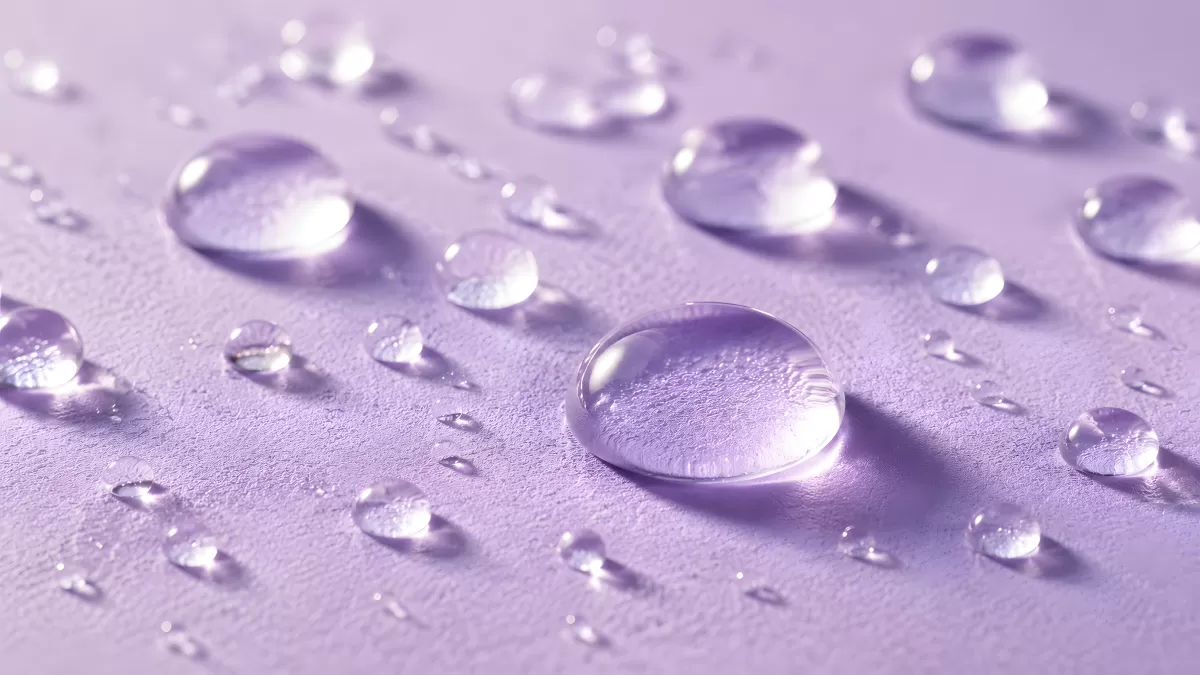 Wassertropfen auf violetter Oberfläche in Nahaufnahme