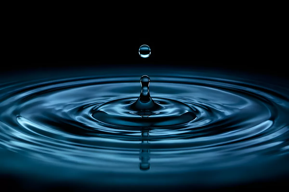 Wassertropfen fällt auf ruhige Oberfläche mit Wellen