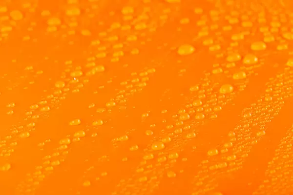 Water drops over orange background, close up