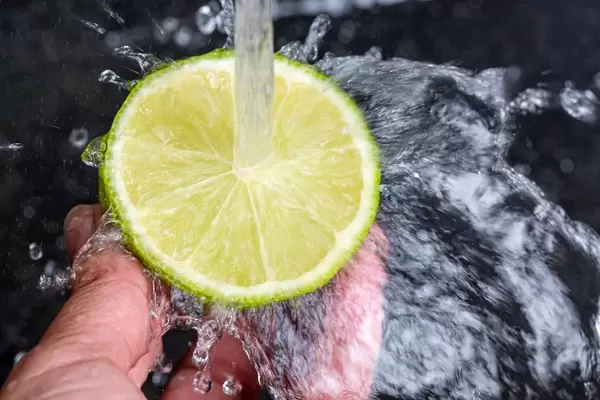 Water pours on half a ripe lime and splashes