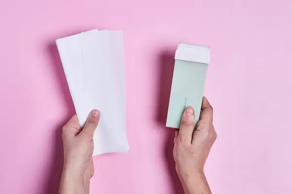 Wax strips in female hands over colored background