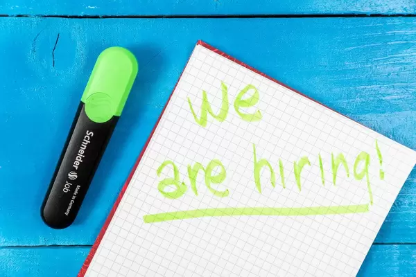 We Are Hiring sign on the paper with green pencil