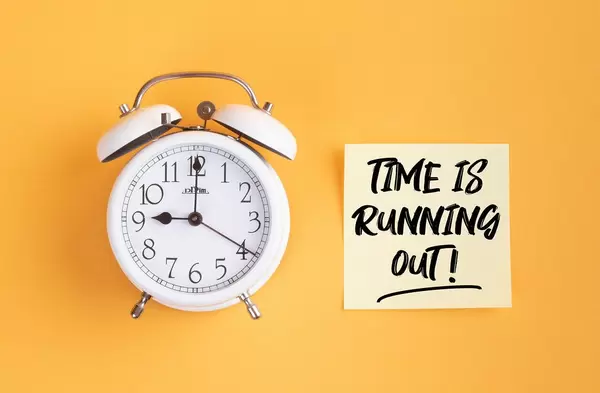 Wecker und ein Zettel mit ‘Time is running out!’ Text vor gelbem Hintergrund