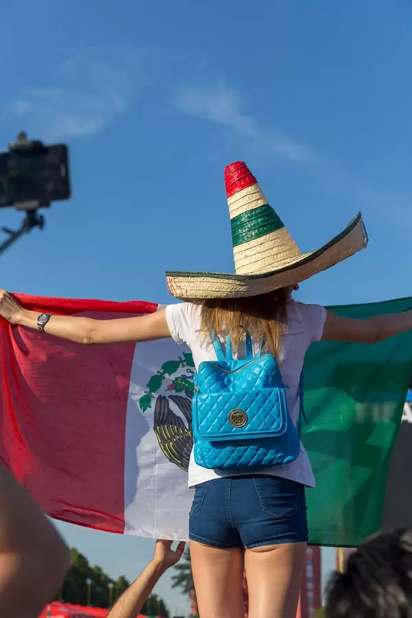 Weiblicher Fußballfan mit Sombrero und mexikanischer Flagge