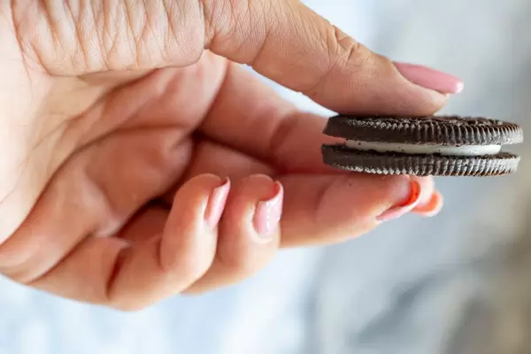 Weiblicher Hand hält einen Oreo Keks mit Vanille Füllung