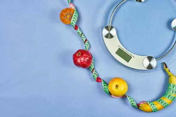 Weight scale and fruits tied with measuring tape