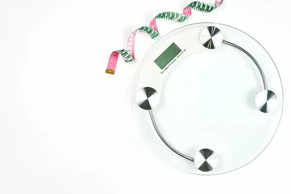 Weighting scales with a measuring tape on white background