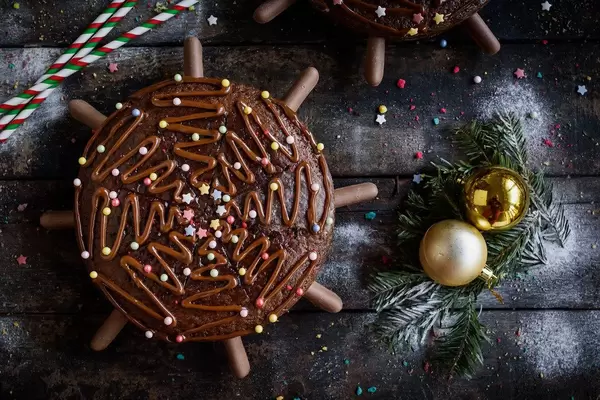 Weihnachts Schokoladenkuchen mit Tannenzweigen und goldenen Weihnachtsbaumkugeln auf Holztisch