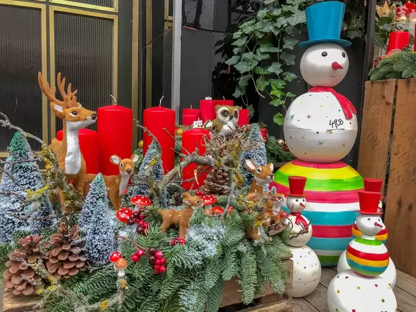 Weihnachtsdekoration mit Tannenzweigen, roten Kerzen, Schneemännern mit rotem Hut und bunten Steifen, Rehen und einem Hirsch, Eule, Tannenzapfen und Fliegenpilzen