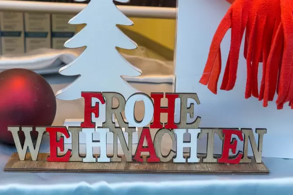 Weihnachtsdekoration Schriftzug frohe Weihnachten, weißer Tannenbaum und rote Weihnachtskugel
