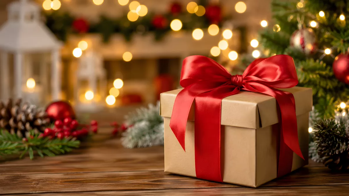 Weihnachtsgeschenk mit roter Schleife vor Lichterkette