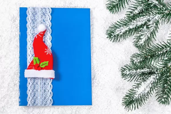 Weihnachtsgrußkarte in blau mit Weihnachtsmannmütze im Schnee