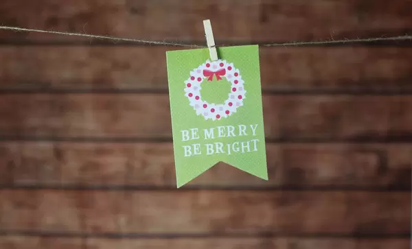Weihnachtskarte "Be merry, be bright" hängt mit Klammer an Leine