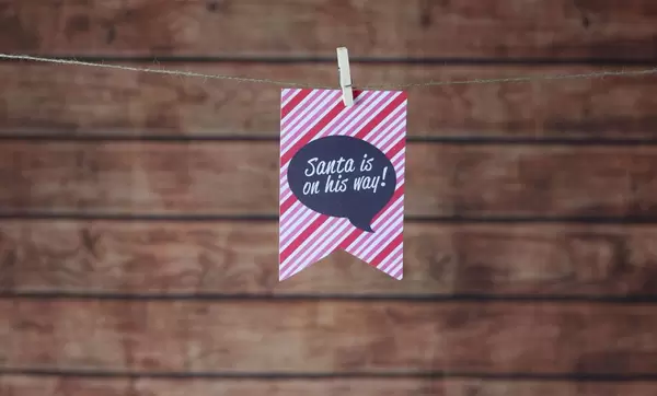 Weihnachtskarte "Santa is on his way" mit Holz im Hintergrund