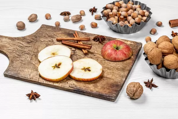 Weihnachtsstimmung: Verschiedene Nüsse, geschnittene Äpfel und Gewürze auf Holztisch