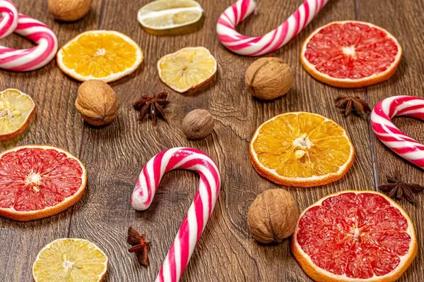 Weihnachtsstimmung: Weihnachtslutscher mit getrockneten Zitrusfrüchten auf einem Holztisch