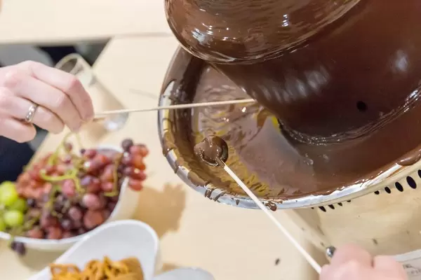 Weintrauben an Spießen in einem Schokoladenbrunnen
