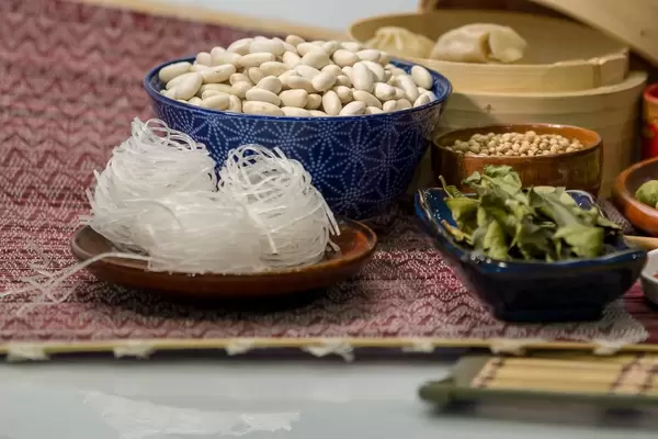 Weisse Bohnen, Glasnudeln und getrocknete Kräuter in Porzellanschalen