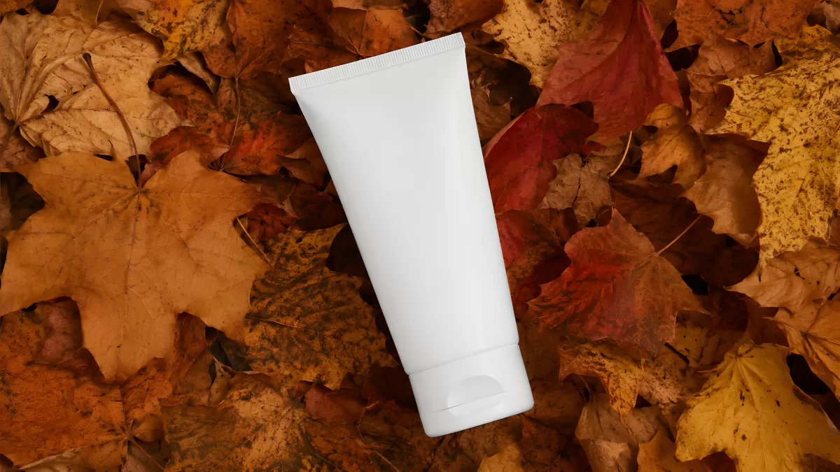 Weiße Cremetube auf bunten Herbstblättern