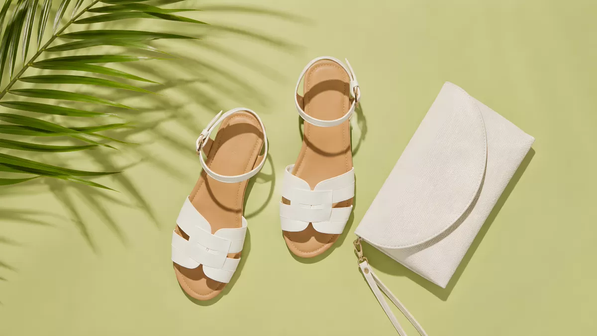 Weiße Sandalen und Clutch auf hellgrünem Hintergrund