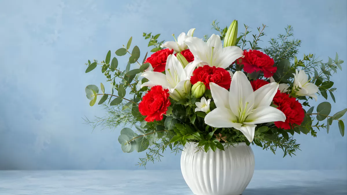Weißer Strauß mit roten Nelken und Lilien in Vase