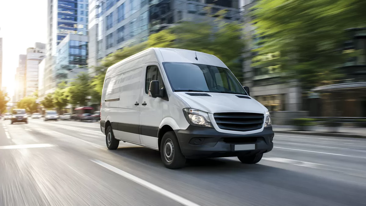 Weißer Transporter fährt schnell durch Stadtstraße
