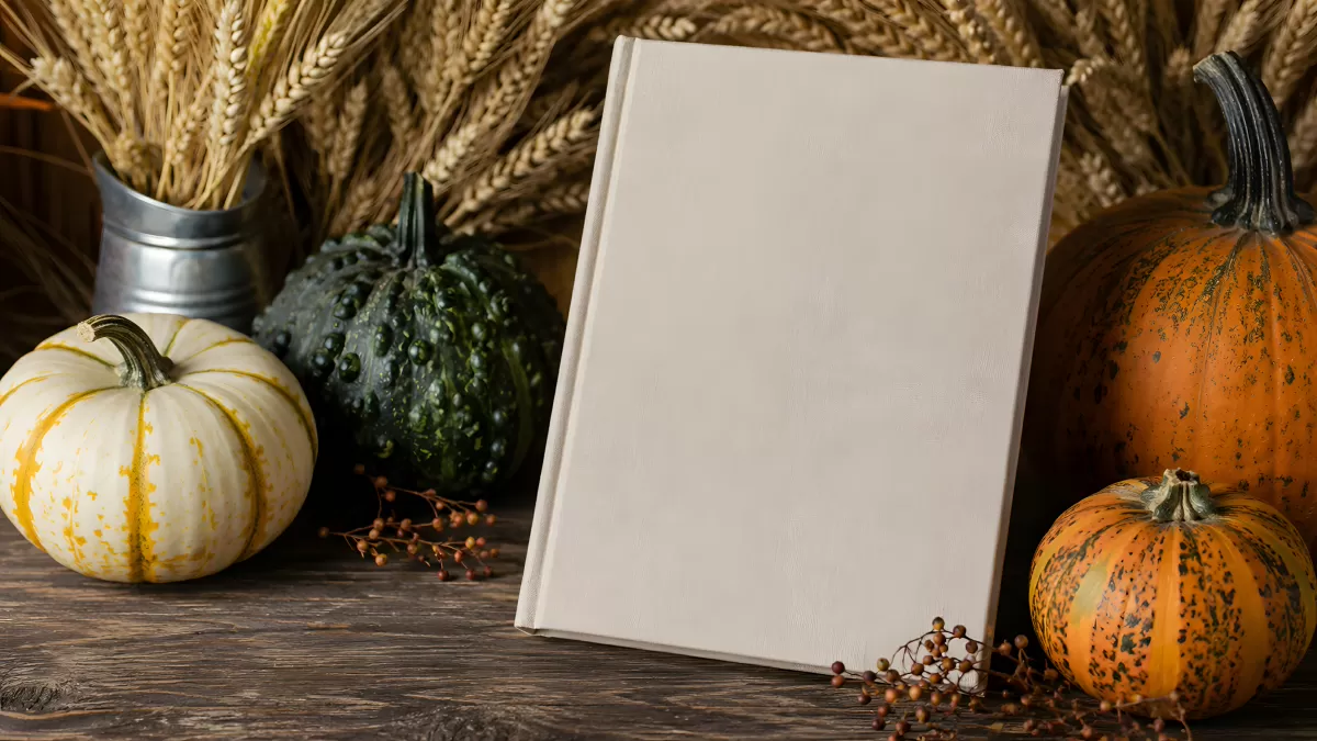 Weißes Hardcover-Buch zwischen Kürbissen im Herbst