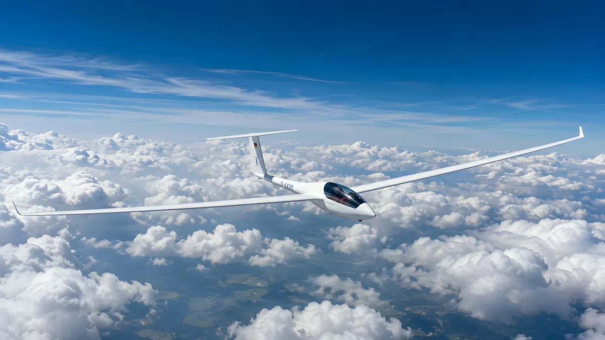Weißes Segelflugzeug gleitet über Wolkendecke am blauen Himmel