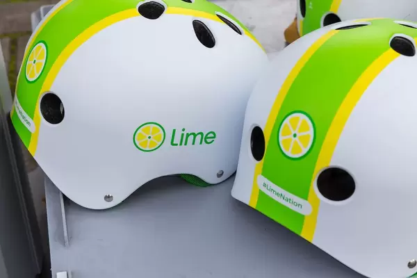 Weiß-grün-gelbe Sturzhelme mit Lime Logo und #LimeNation Hashtag für sichere E-Scooter Fahrten