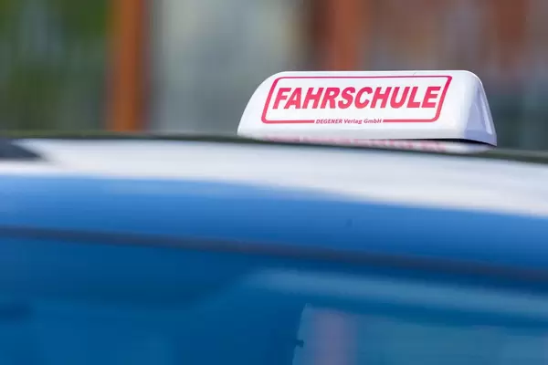 Weiß-roter Schild auf blauem Fahrschulauto