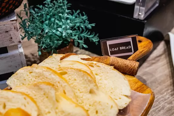 Weißbrot in Scheiben geschnitten auf einem Holzbrett am Frühstücksbüfett