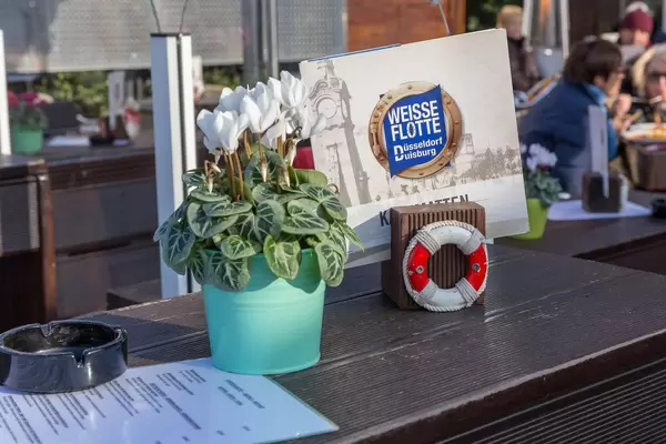 Weiße Blumen und eine Getränkekarte auf dem Tisch in einem Lokal